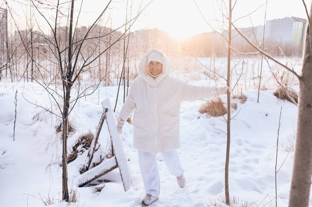 Felice anziana donna anziana matura in bianco caldo outwear giocare con la neve in inverno soleggiato all'aperto. Pensionati persone sane vacanze vacanza attività invernali, concetto di stile di vita attivo - Foto, immagini