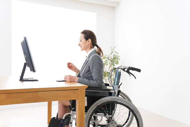 Jonge vrouw werkt in een rolstoel - Foto, afbeelding