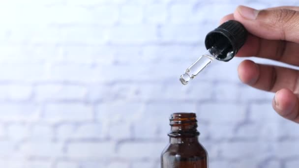 La goccia cade da una pipetta in una bottiglia cosmetica - Filmati, video