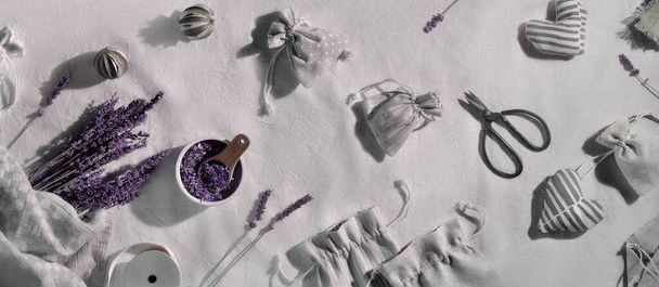 Dry lavender flowers, panoramic composition. Hand made lavender sachets in textile bags and cotton hearts on cotton tablecloth,. Low impact lifestyle. Dry lavender flowers and essential oil. - Foto, Bild