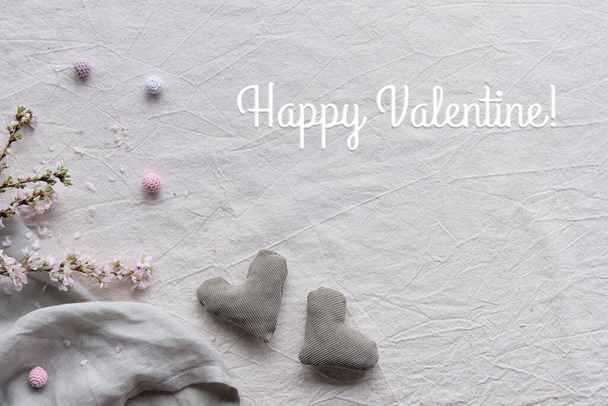 Hand made textile hearts and balls on cotton background. Textile handicraft in neutral colors. Text Happy Valentine. Wintertime cherry flower twigs. Monochrome look, natural light, desaturated hues. - Foto, afbeelding