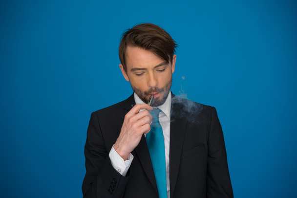 biznesmen z e papierosa na sobie garnitur i krawat na niebiesko - Zdjęcie, obraz