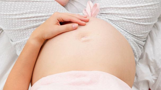 子供を期待して妊娠中の若い女性は、彼女の腹に撫でて優しく触れます.美しい妊娠と赤ちゃんの期待 - 写真・画像