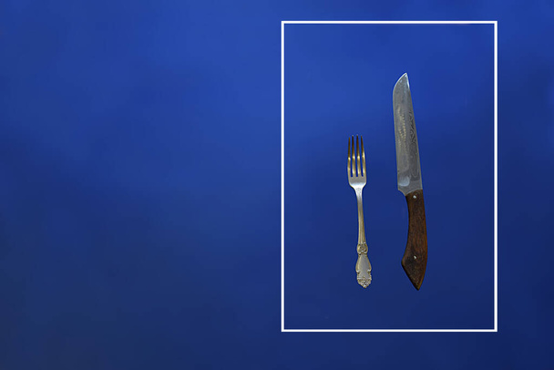 Vidlička a nůž v rámu na modrém pozadí. Koncept dopravní značky. - Fotografie, Obrázek