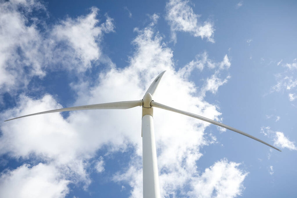 Windkraftanlage an einem sonnigen Tag mit blauem Himmel und Wolken. Ökofeld Windpark. Grüne ökologische Stromerzeugung. - Foto, Bild