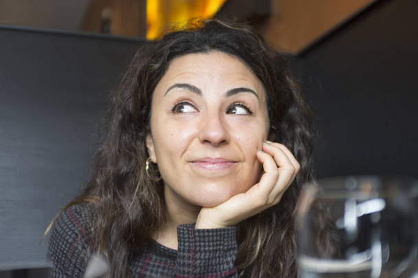 Portrait de femme souriante reposant son menton sur la main au restaurant - Photo, image