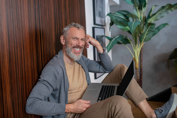 Grey-haired mature confident man working at home and feeling good - 写真・画像