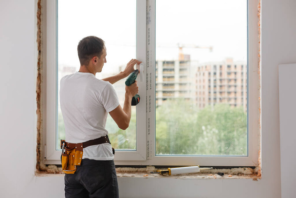 Junger Handwerker repariert Fenster mit Schraubenzieher - Foto, Bild
