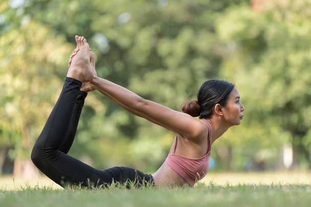 Mujer asiática haciendo ejercicio de yoga y relajarse con ropa deportiva en el parque, deporte y estilo de vida saludable concepto - Foto, imagen