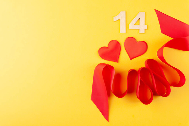 Wunderschönes rotes Herz und geschwungene Schleife, Valentinstag und Liebe auf gelbem Hintergrund - Foto, Bild