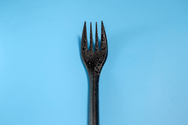 Fourchette en plastique noir sur fond bleu - Photo, image