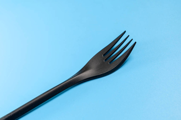 Black plastic fork on a blue background - Foto, immagini