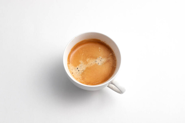 Een witte keramische kop vers gebrouwen koffie. Koffiemelk op het drankje. - Foto, afbeelding