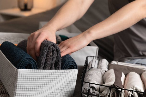 Armazenamento vertical de roupas. As mulheres organizam roupas em um quarto moderno. Mulheres classificando roupas em cestas conceito de limpeza da sala. - Foto, Imagem