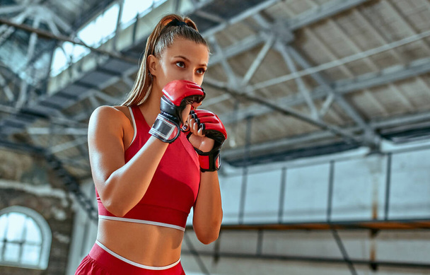 Sportliches Mädchen macht Boxübungen, macht einen direkten Tritt. Foto eines jungen Mädchens in einem Sportverein oder Fitnessstudio. Stärke und Motivation. - Foto, Bild