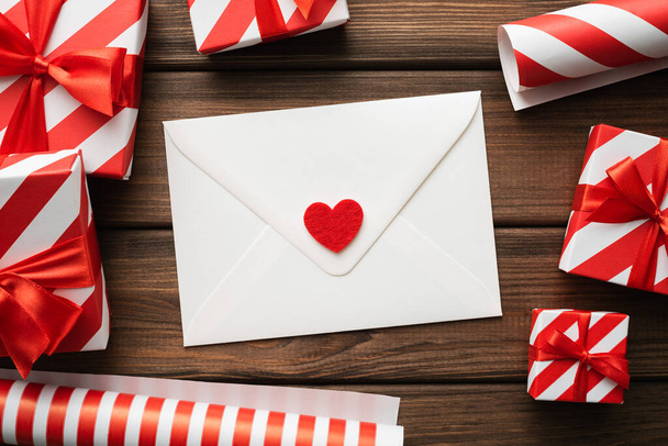 День Святого Валентина вітальна листівка з подарунковими коробками на старовинному дерев'яному фоні та білий конверт з серцем
 - Фото, зображення