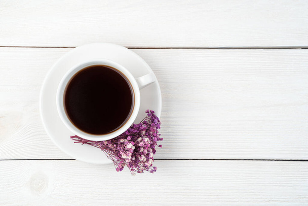 Eine Tasse Kaffee und ein Blumenstrauß auf weißem Hintergrund. Ansicht von oben, mit Platz zum Kopieren. - Foto, Bild