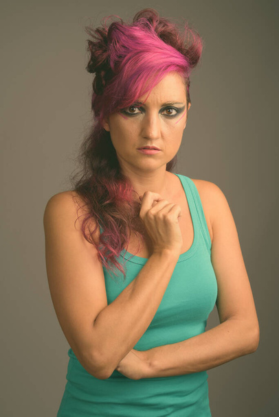 Beautiful woman with pink hair and make-up against gray background - Photo, image