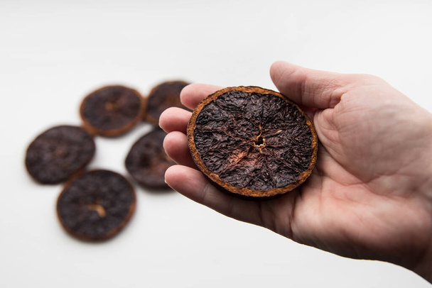  Failure at drying orange slices in oven. Person hand holding a dry and over burnt charred fruit. - Photo, image