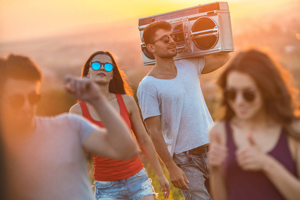 The four young people with a boom box dancing on the sunny background - Photo, Image