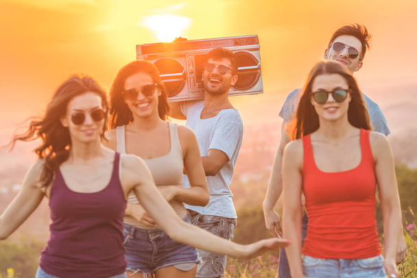 The happy friends with a boom box dancing on the bright sun background - Photo, Image