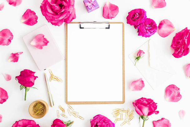 Composición con portapapeles, cuaderno, rosas flores y accesorios sobre fondo blanco. Piso tendido, vista superior. - Foto, imagen