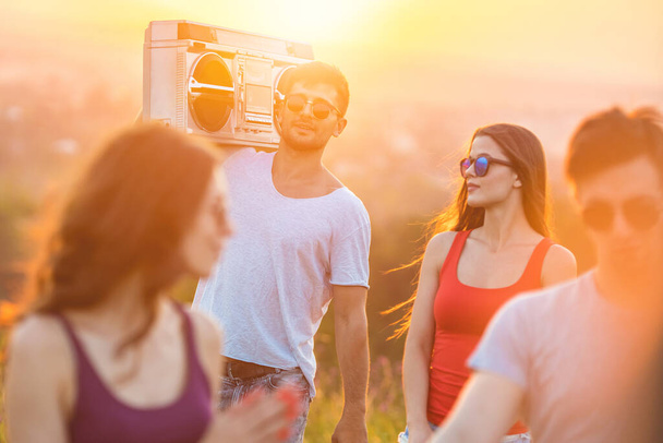 Die glücklichen Menschen stehen mit einer Boom-Box auf dem strahlenden Sonnenhintergrund - Foto, Bild