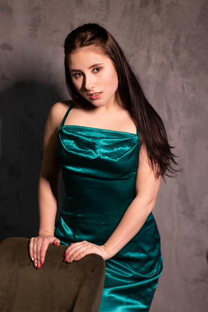 sexy attractive brunette woman in elegant green aquamarine dress in a loft cafe. beautiful sensual girl. copy space. - Photo, image