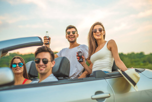 The four happy people sit in a cabrio - Фото, изображение