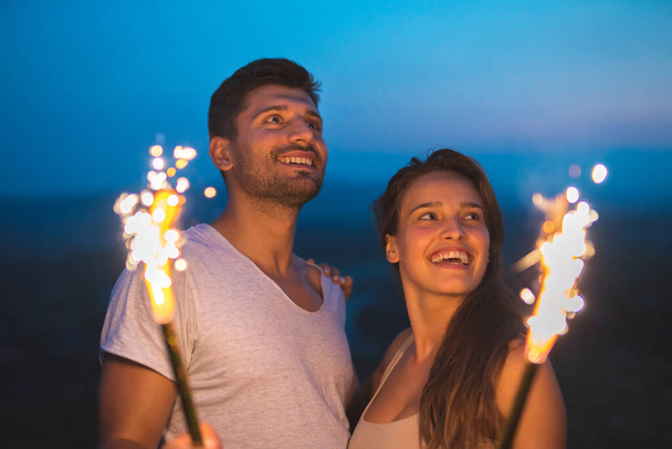 The happy couple hold a firework sticks. evening night time - Zdjęcie, obraz