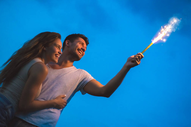 L'homme et la femme heureux tiennent un bâton de feu d'artifice. soir heure de nuit - Photo, image