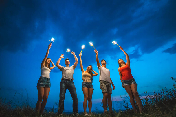 Šťastní přátelé drží ohňostroje. večerní čas - Fotografie, Obrázek