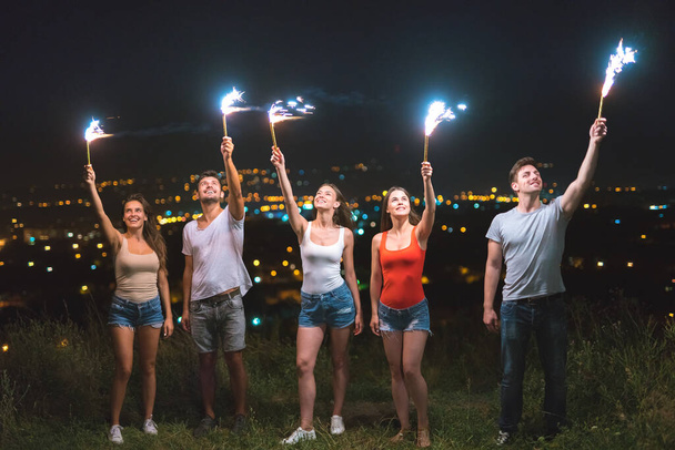 Счастливые люди держат в руках фейерверки. вечернее время - Фото, изображение