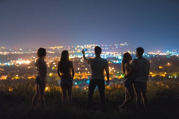 Le cinque persone fanno un selfie sullo sfondo della città. sera notte - Foto, immagini
