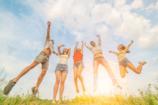 Los cinco amigos felices saltando sobre un fondo soleado - Foto, Imagen