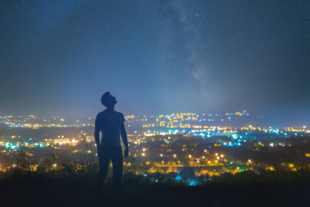 El hombre de pie en el fondo de la estrellada sobre la ciudad de la noche - Foto, imagen