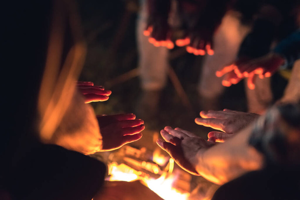 Die Menschen wärmen sich am Lagerfeuer die Hände. Nachts - Foto, Bild