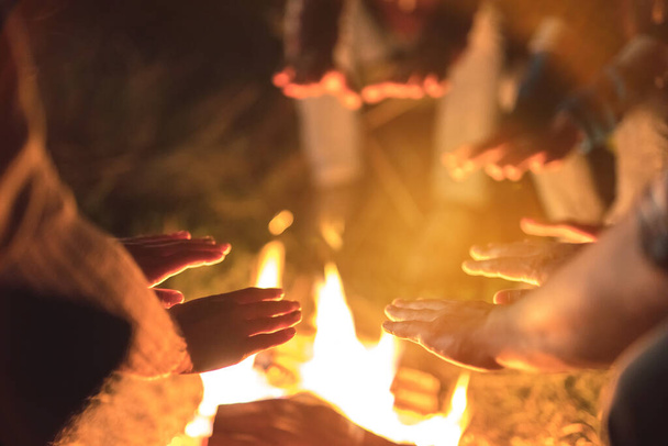 人々はたき火の近くで手を暖める。夜の時間 - 写真・画像
