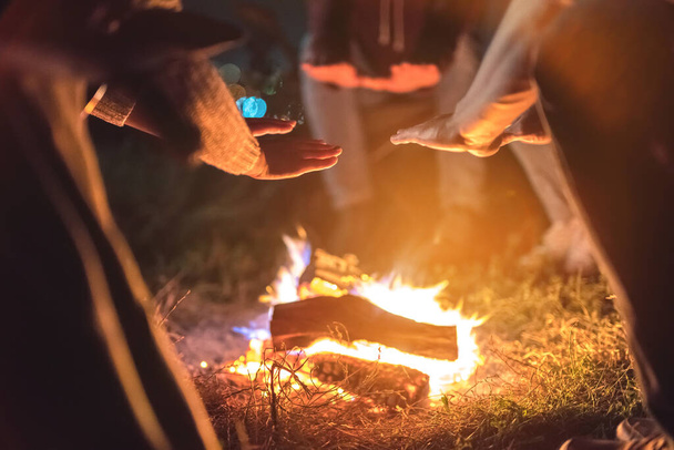 Die Menschen wärmen sich an einem Lagerfeuer die Hände. Abend Nacht - Foto, Bild