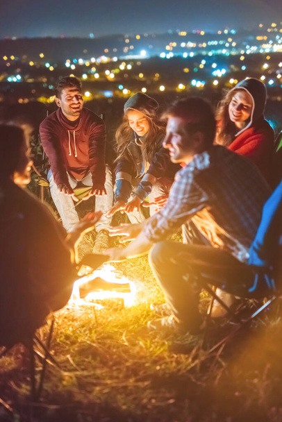 Die fröhlichen Menschen wärmen Hände über dem Lagerfeuer. Abend Nacht - Foto, Bild
