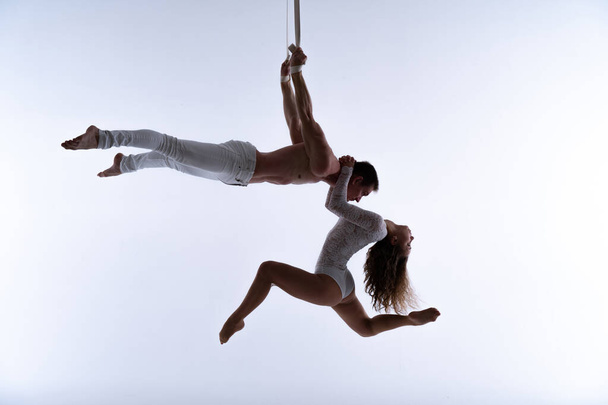 Aerial straps duo wearing white costume on white background doing performance  - Φωτογραφία, εικόνα
