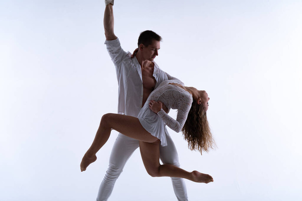 Aerial straps duo wearing white costume on white background doing performance in slow motion. Concept of desire, attraction and relationship - Photo, image