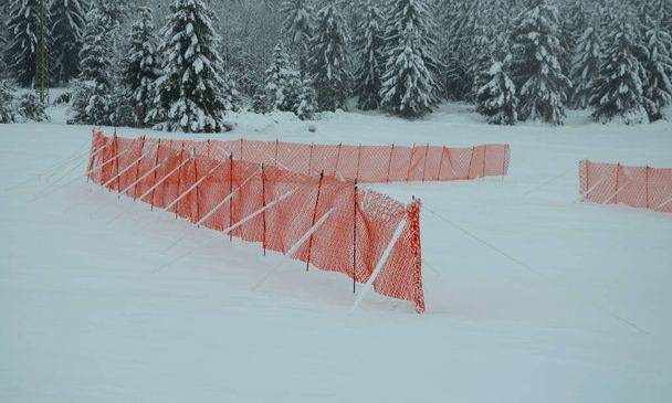 barrière en plastique perforé orange en PE contre la neige dans les zones de montagne. ralentir la vitesse de la neige, formant des langues et des barrières dunaires sur la chaussée. Il protège le brise-vent pendant le blizzard  - Photo, image