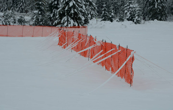 orange perforated plastic PE foil barriers against snow in mountain areas. slow down the speed of snow, forming tongues and dune barriers on the highway roadway. It protects windbreak during blizzard  - Photo, Image