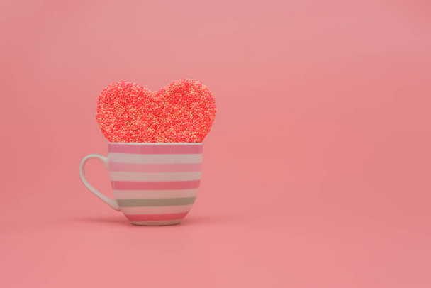 Big heart in a cup on pink background. Love, wedding and Valentine's day celebration concept. Copy space - Фото, зображення