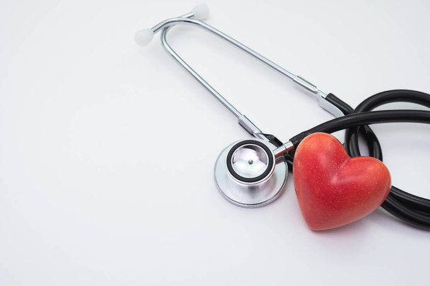 stethoscope and red artificial heart on a white background on the table - Foto, Imagem