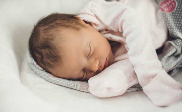 Bebé recién nacido durmiendo bien mientras usa ropa de abrigo y acostado en un sofá de bebé - Foto, imagen