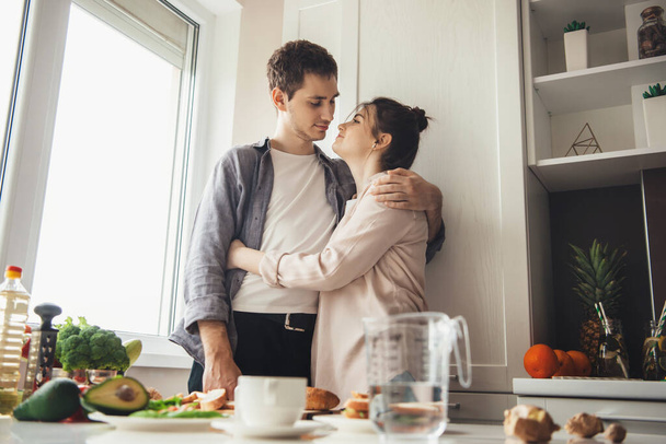 Charmantes Paar bereitet gemeinsam in der Küche das Abendessen zu, während der Ehemann seine Geliebte umarmt - Foto, Bild