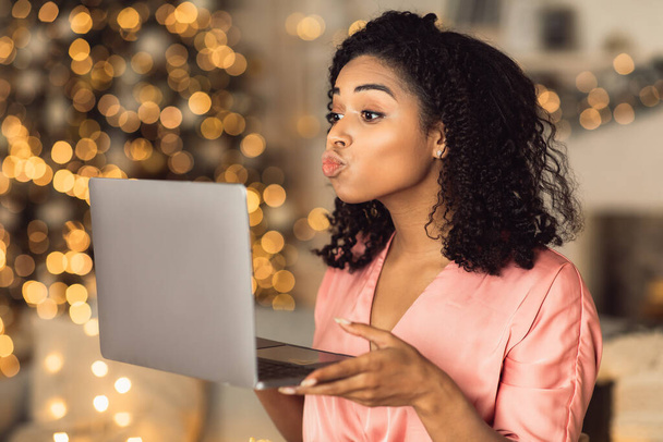 Afro woman blowing kiss during virtual date on laptop - Photo, image