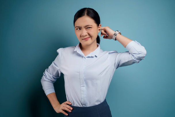 Азиатская женщина зудит и сует палец в уши стоя изолированно на синем фоне. - Фото, изображение